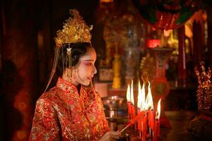 Chinesisch Frau machen wünscht sich, beten, und Licht Kerzen. auf das Gelegenheit von das jährlich Chinesisch Neu Jahr Festival, im ein verehrt Schrein oder Tempel foto