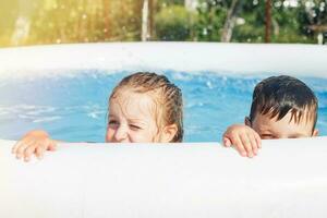 Porträt von glücklich Junge und Mädchen im das Schwimmbad im das Garten beim Sommer- foto