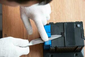 Schärfen eines Messers auf einem elektrischen Schärfer zu Hause. die hand des mannes treibt die messerklinge zwischen die blauen spitzer, staub fliegt auf die maschine. foto