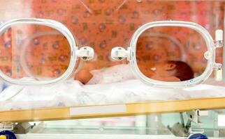 Nahansicht krank Neugeborene Baby Schlaf im ein Baby Inkubator im ein Krankenhaus. foto