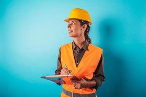 zuversichtlich Frau Architekt mit ein Orange Helm tut ein skizzieren foto