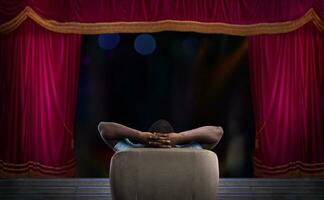 Mann entspannend auf ein Sessel und Uhren ein Show im ein Theater foto