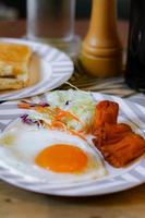 Frühstück, gebraten Eier, gebraten Wurst, Gemüse Salat und Toast auf ein braun hölzern Tabelle mit Kaffee. foto