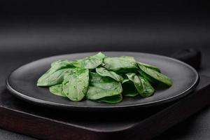 frisch Grün Spinat Blätter auf ein schwarz Keramik Teller foto