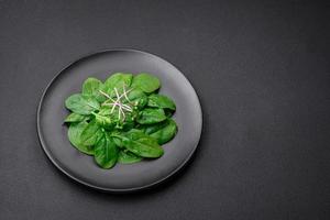 frisch Grün Spinat Blätter auf ein schwarz Keramik Teller foto