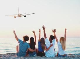 Gruppe von freunde haben Spaß auf das Strand mit fliegend Flugzeug foto