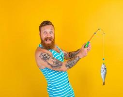 Mann mit Bart und Badeanzug gefangen ein Fisch foto