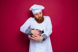 Koch mit Bart und rot Schürze ist eifersüchtig von seine Rezept foto