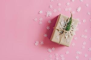 braun Geschenk Box auf das Rosa Hintergrund mit Weihnachten Dekoration. minimal gestylt Urlaub Karte mit Kopieren Raum. foto