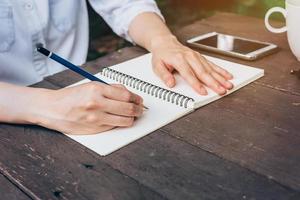 Hipster Frau Hand Schreiben Notizbuch Papier im Kaffee Geschäft. foto