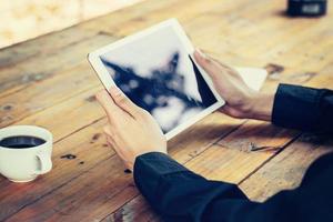 Geschäft Mann Hand halten Tablette auf Tabelle im Kaffee Geschäft mit Jahrgang getönt Filter. foto