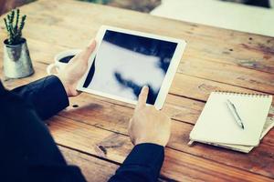 Geschäft Mann Hand halten und mit Tablette auf Tabelle im Kaffee Geschäft mit Jahrgang getönt Filter. foto