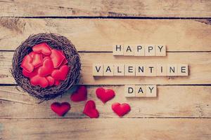 rot Herz im Nest mit hölzern Text glücklich Valentinstag Tag auf Holz Tabelle Hintergrund. foto