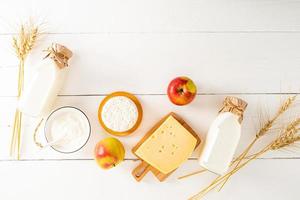 traditionell Molkerei Produkte, Milch, sauer Creme, Äpfel auf ein Weiß hölzern Hintergrund gemacht von Bretter mit hölzern Briefe von glücklich Schawuot. oben Sicht. foto