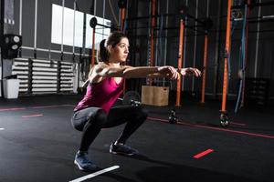 sportlich Mädchen tut Hocken Übungen beim das Fitnessstudio foto