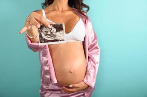 schwanger Mama zeigt an ein Ultraschall von ihr Sohn foto