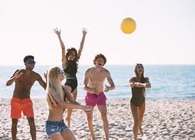 Gruppe von freunde spielen beim Strand Volley beim das Strand foto