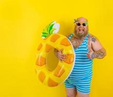 Fett glücklich Mann mit Perücke im Kopf ist bereit zu schwimmen mit ein Krapfen Lebensretter foto