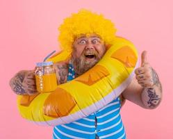 Fett glücklich Mann mit Perücke im Kopf ist bereit zu schwimmen mit ein Krapfen Lebensretter foto