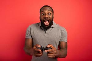 glücklich Mann Theaterstücke mit ein Videospiel auf rot Hintergrund foto