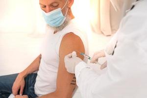Arzt verwaltet das Impfstoff gegen covid-19 zu das geduldig mit das Spritze foto