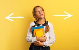 jung Schüler ist verwirrt Über das richtig Pfeil zu wählen. Gelb Hintergrund foto