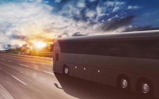 großartig Tour Bus ziehen um schnell auf das Autobahn beim Sonnenuntergang foto