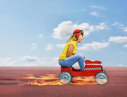 Frau mit rot Helm fährt ein schnell Spielzeug Auto auf das Spur foto