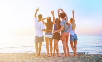 Gruppe von glücklich freunde haben Spaß beim Ozean Strand beim Dämmerung foto