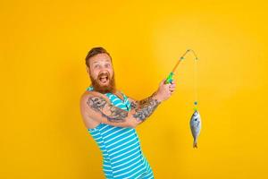Mann mit Bart und Badeanzug gefangen ein Fisch foto
