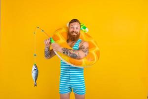 glücklich Mann mit Bart und aufblasbar Krapfen fängt Fisch foto