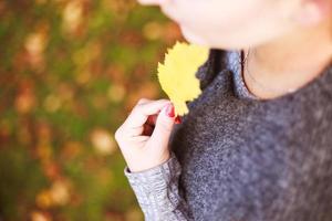 Porträt von ein Mädchen mit ein Herbst Blatt im ihr Hand foto