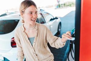 Frau beim das Gas Bahnhof zahlt sich aus mit das Anerkennung Karte foto