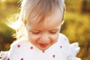 Porträt von ein wenig glücklich Mädchen draussen . das Kind lächelt und zeigt an das Zunge foto