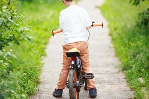 Junge mit ein Fahrrad auf das Straße foto