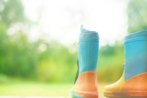 Gummi Stiefel auf ein hölzern Hintergrund. Kinder- Gummi Stiefel auf ein Hintergrund von Grün Gras foto
