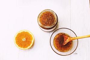 Stachelbeere und Orange Marmelade im ein Glas Schüssel mit ein hölzern Löffel auf ein Weiß Hintergrund foto