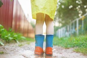 Kind im Gummi Stiefel spielen im ein Pfütze foto