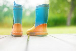 Gummi Stiefel auf ein hölzern Hintergrund. Kinder- Gummi Stiefel auf ein Hintergrund von Grün Gras foto