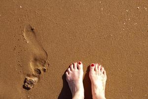 ein Mensch Schritte und weiblich Füße auf ein sandig Strand foto