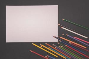 mehrfarbige Stifte und weißes Papier auf schwarzem Hintergrund foto