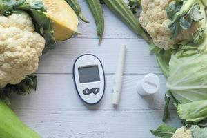 Messgeräte für Diabetiker und frisches Gemüse auf dem Tisch foto