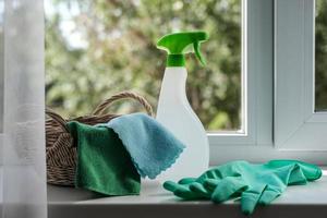 Putzmittel, Tücher und Gummihandschuhe in einem Körbchen auf der Fensterbank. Allgemeines Reinigungskonzept foto