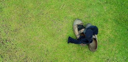 oben Aussicht von alt Schuhe und schwarz Socken Putten auf Grün Gras Feld Hintergrund mit links Kopieren Raum. benutzt Objekt und Leben Stil Konzept foto