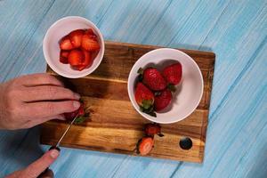 Draufsicht einer Person, die Erdbeeren schneidet foto