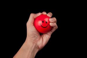 Hand drückt einen roten Stressball foto