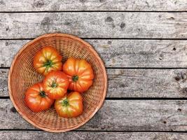 Tomaten in einem Weidenkorb auf einem hölzernen Tischhintergrund foto