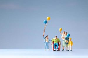 Miniaturmenschen zeigen eine positive Familie, die sich um ihren behinderten Vater kümmert foto