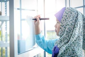 islamisch Mädchen studieren im Schule und Schreiben Zahlen auf das Tafel. Konzept von lehrreich Entwicklung von Kinder im Asien foto