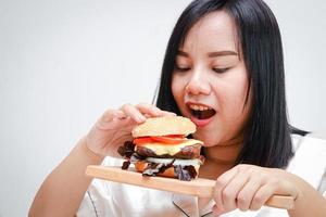 Fett asiatisch Frauen Essen groß Hamburger, Weiß Hintergrund. Gesundheit Konzept. Menschen Wer sind Übergewicht. foto